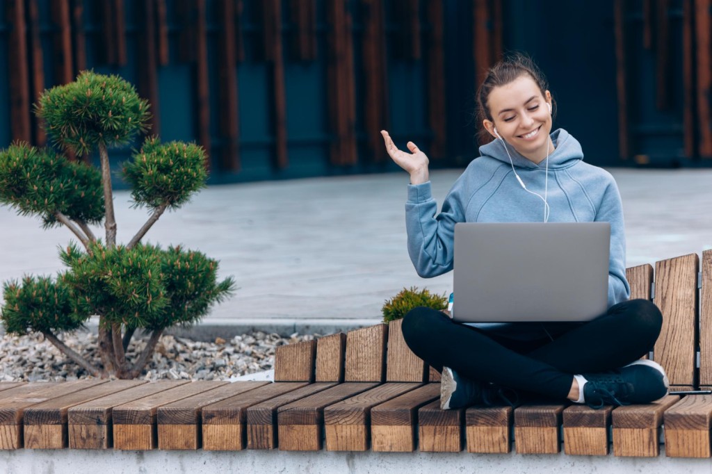 Frau lernt mit einem Laptop auf einer Bank in der Natur