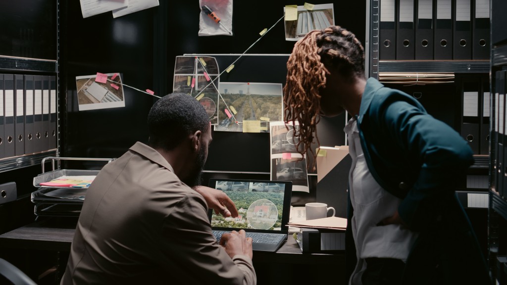 Case files, statements, court documents: the working language of German forensic practice is the reason these programmes are not offered in English. A man and a woman in an archive room going through case files and written statements at a desk with a laptop