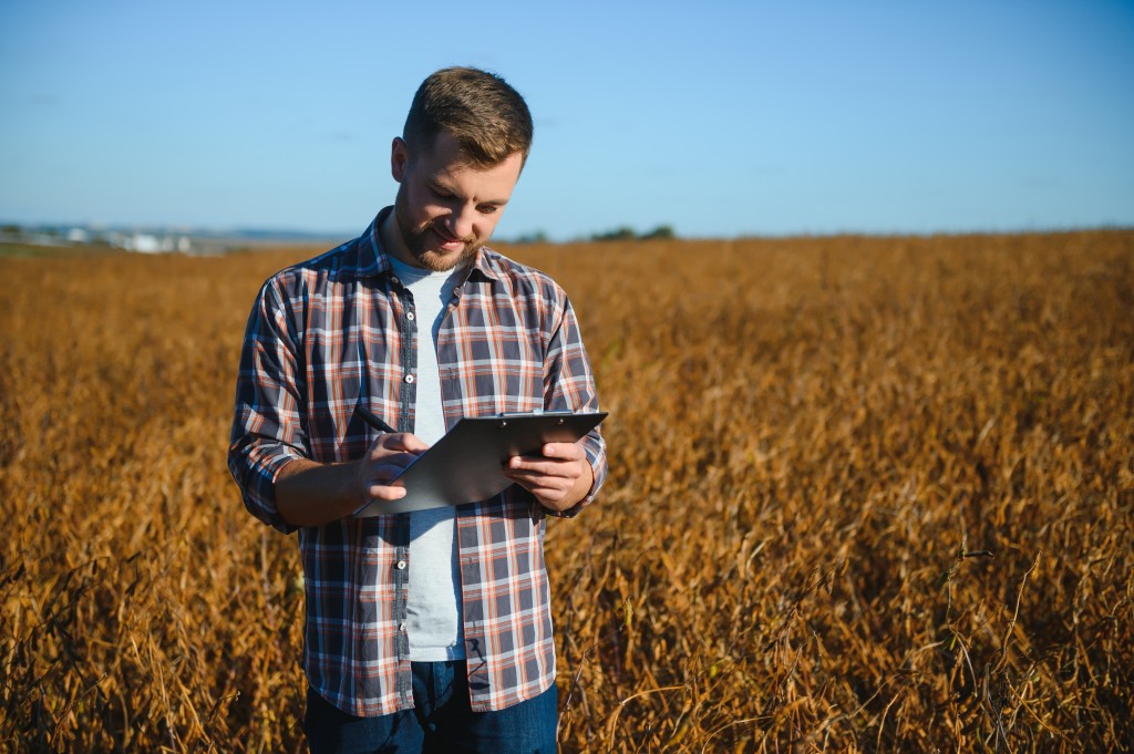 Digitale Bestandsführung gehört längst zum Berufsbild. Genau dort setzen die berufsbegleitenden Programme an. Mann steht mit einem Tablet in einem Feld und begutachtet den Pflanzenbestand