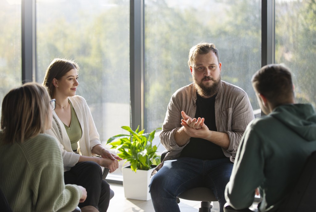 Group of students sitting in a circle in a bright seminar room, talking