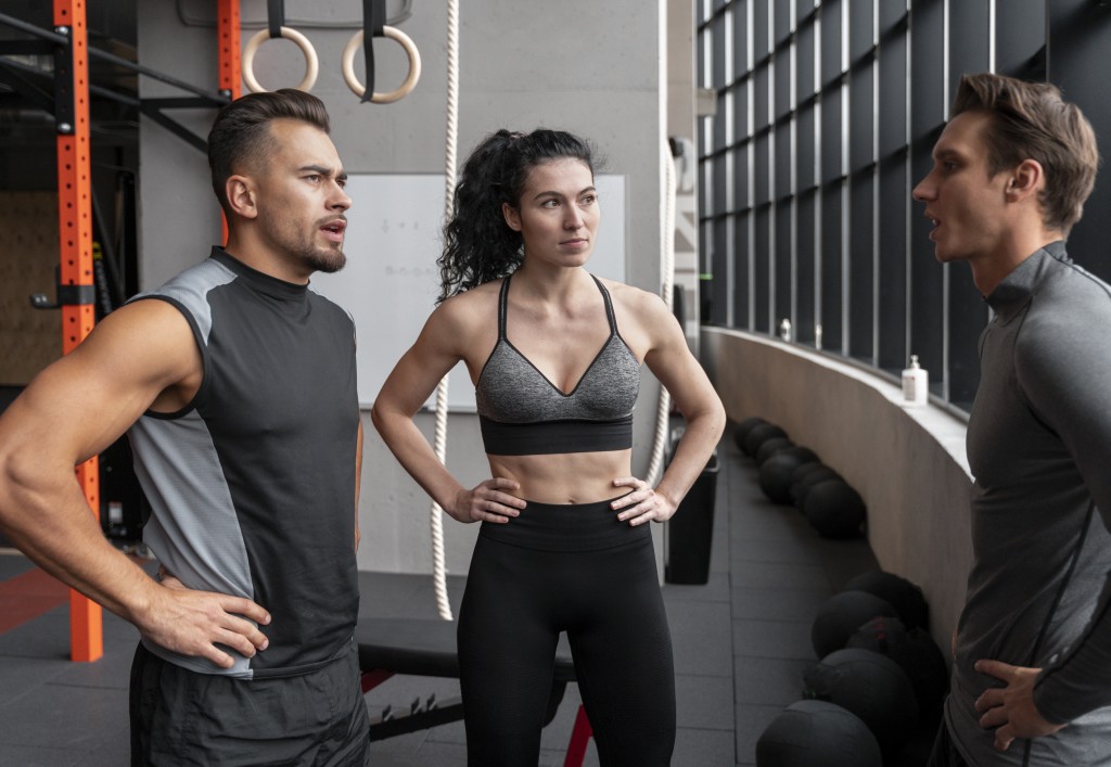 In der dualen Ausbildung lernen Auszubildende im Studio, den schulischen Teil übernimmt die Akademie im Blockunterricht und digital. Trainerin und Trainer besprechen im Fitnessstudio einen Trainingsplan mit Mitgliedern