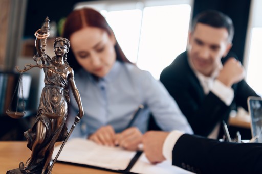 Kleine Justitia-Figur mit Waage auf einem Schreibtisch neben Unterlagen