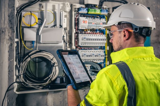 Im Fernlehrgang lernst du nach Feierabend, die Praxis läuft im Job weiter – sie zählt für die Prüfungszulassung mit. Elektrotechniker prüft einen Schaltschrank und dokumentiert die Messwerte auf einem Tablet
